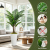 Artificial palm tree floor decor in a white pot placed indoors near a window.