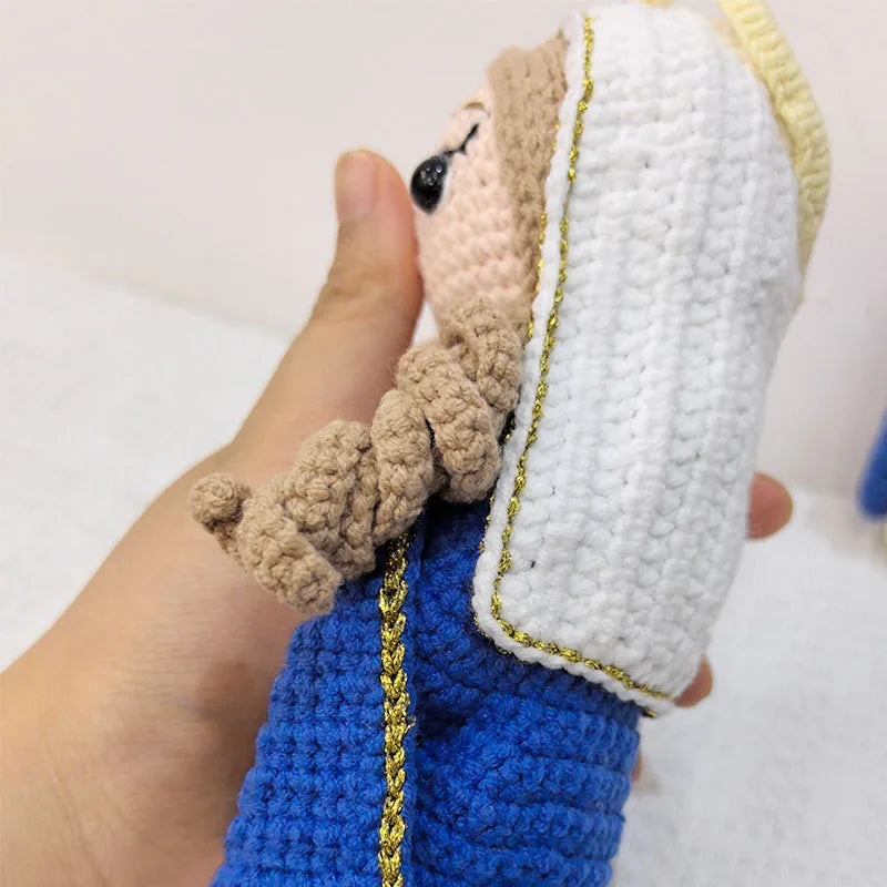 Handcrafted Virgin Mary crochet doll with a light brown beard and white garment held by a hand