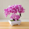 A vibrant pink and white artificial bonsai tree decoration planted in a white rectangular pot.