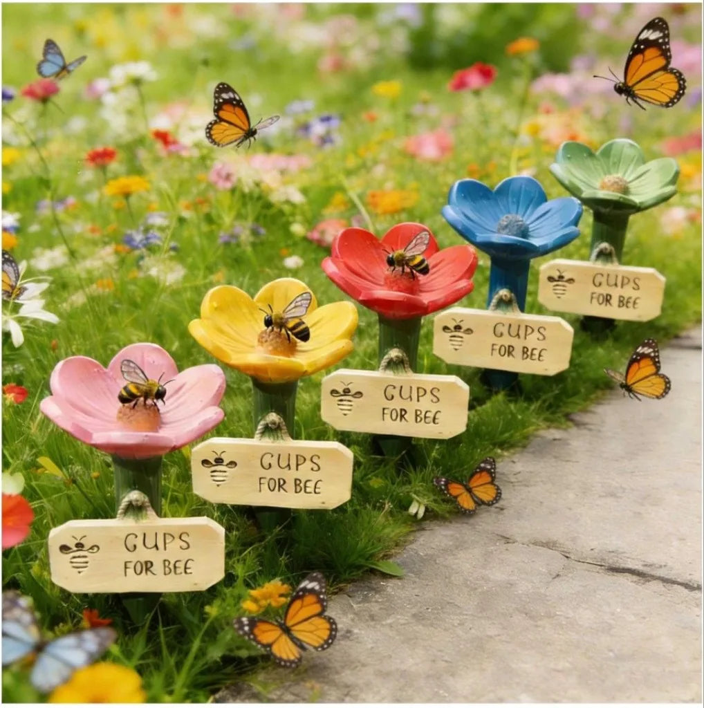 A garden decoration featuring a bee watering station with a ladder among colorful flowers and butterflies.