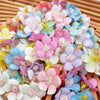 A dense arrangement of silk artificial flower heads in various shades of pink, white, blue, and purple.