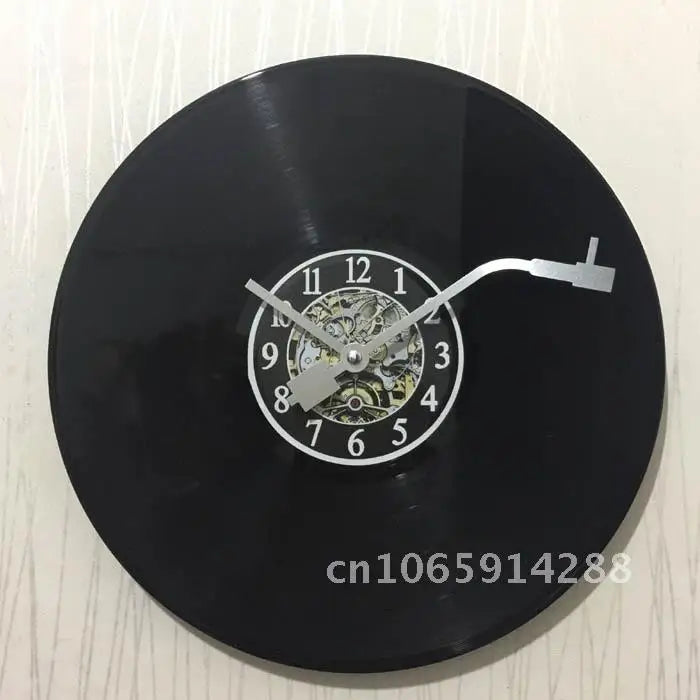 A black decorative vinyl record wall clock with a gold-colored face and hands.