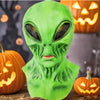 A realistic green alien full-face latex mask displayed in a Halloween context with pumpkins.