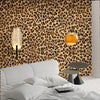 A bedroom featuring a white headboard and bedding against a leopard print wallpaper.