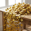 A long, shimmering gold star paper garland draped across a wooden table.