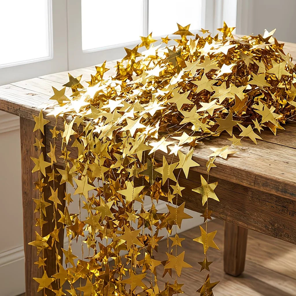 A long, shimmering gold star paper garland draped across a wooden table.