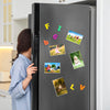 A refrigerator door decorated with colorful magnetic picture frames featuring nature and people.