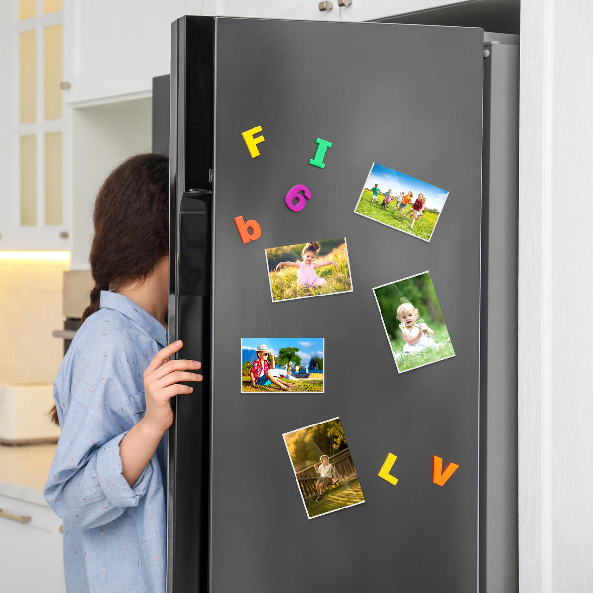 A refrigerator door decorated with colorful magnetic picture frames featuring nature and people.