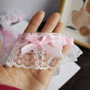 A hand holds a sheer pink lace trim with a delicate bow and ruffle for embroidery or trim.