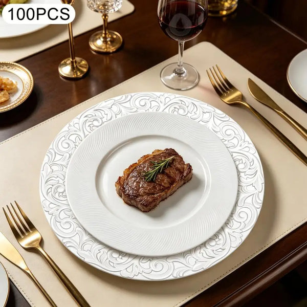 A set of silver embossed charger plates is displayed on a table with a plated steak and silverware.