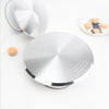 A silver aluminum cake turntable with a rotating platform and a small light-colored object nearby.