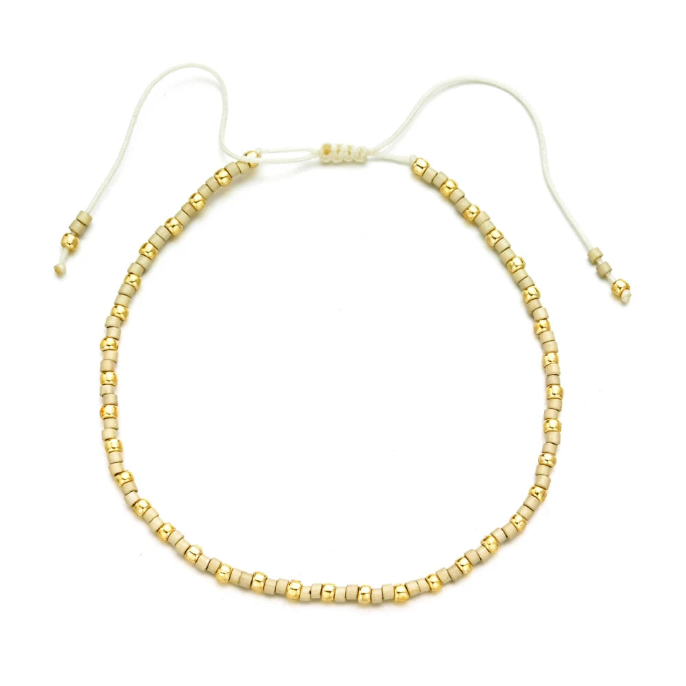 Handmade boho glass bead bracelet with adjustable cord featuring small gold beads.