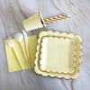 A gold disposable party tableware set including plates, napkins, cups, and straws arranged on a marble surface.