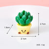 A small potted succulent plant charm made of green resin with a yellow pot and a smiling face.