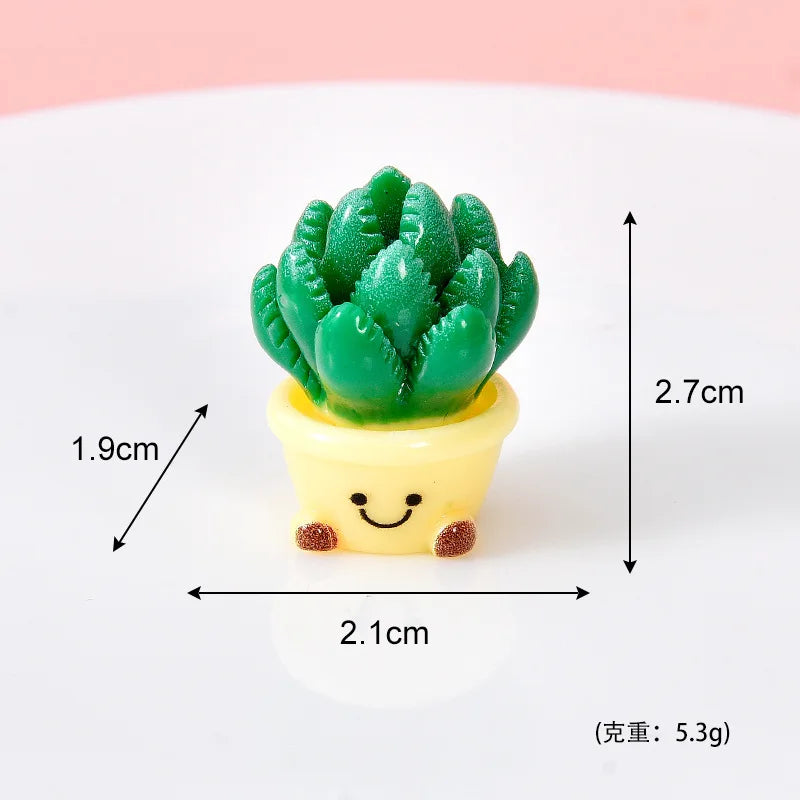 A small potted succulent plant charm made of green resin with a yellow pot and a smiling face.