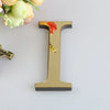 A gold letter I wall decal featuring a reddish-orange floral design against a white background.