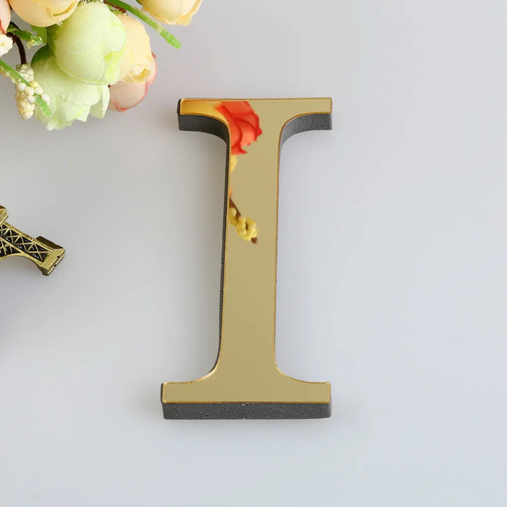 A gold letter I wall decal featuring a reddish-orange floral design against a white background.