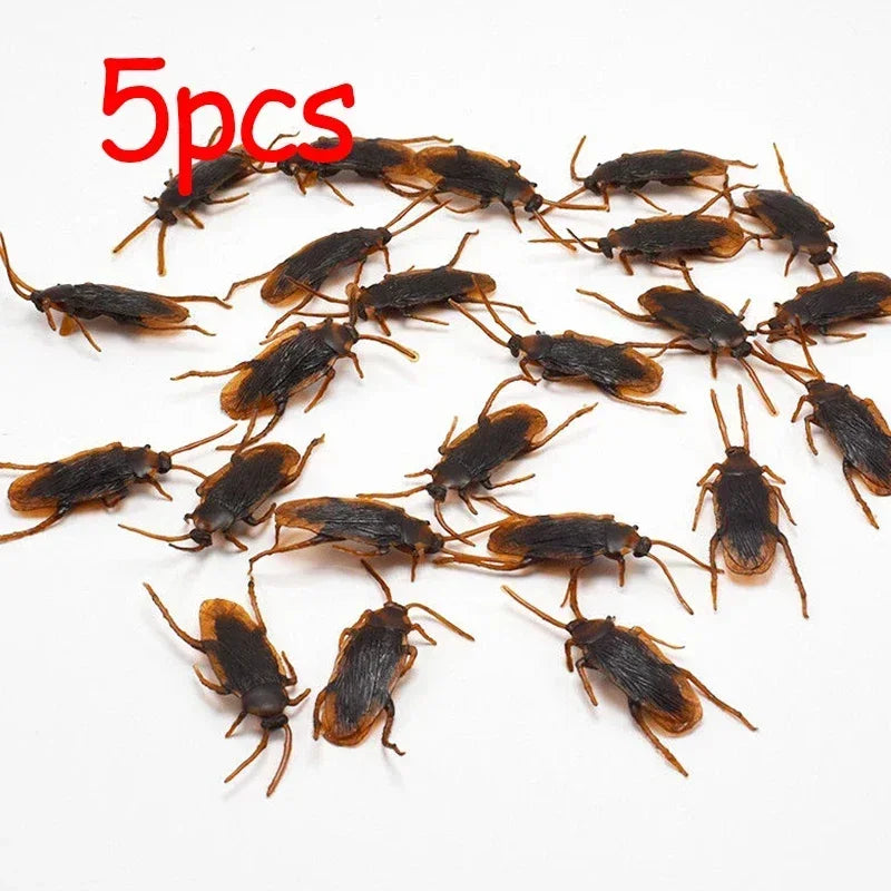 Five plastic cockroach gag toys scattered on a white background.
