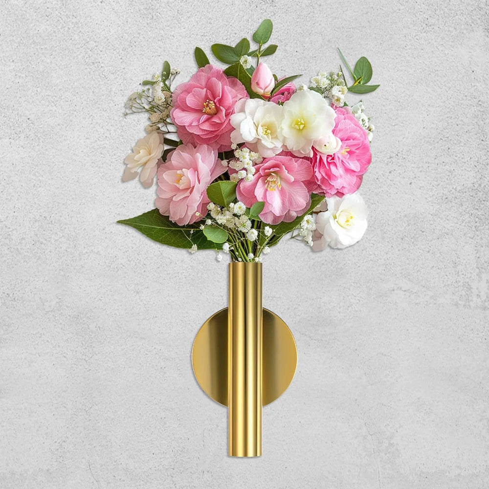 A bouquet of pink and white flowers displayed in a minimalist gold wall-mounted metal vase.