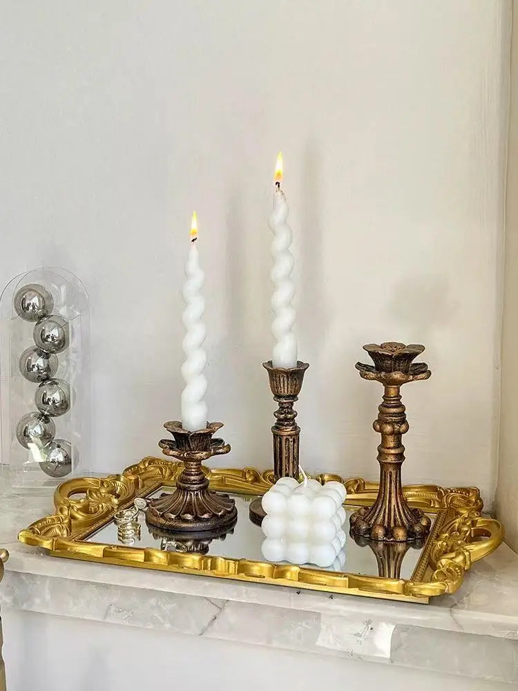 A vintage resin wall sconce candle holder with a white pillar candle and decorative brass accents.