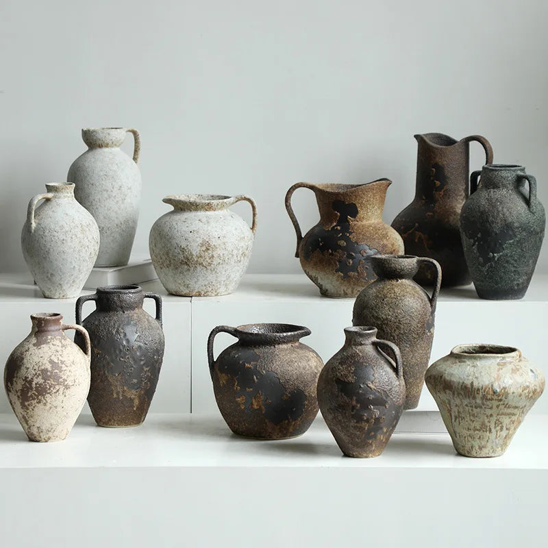 A collection of vintage dual-sided ceramic vases in various earthy tones and textures displayed on a white surface.