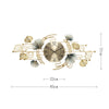 A round metal wall clock featuring decorative leaves resembling ginkgo foliage in gold and silver tones.