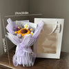 A handmade crochet flower bouquet featuring purple and yellow flowers wrapped in sheer lavender fabric.