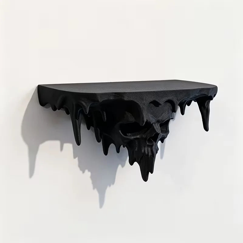 A black, dripping skull wall shelf with a gothic floating display design casting a shadow on a white wall.