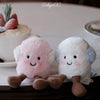 A set of pink and white marshmallow plush toys with brown feet resting on a dark surface.