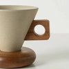 A beige ceramic coffee mug with a wooden handle and base sitting on a light surface.