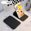 A black portable folding HD makeup mirror with a floral design is shown on a white surface.