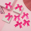 A collection of bright pink satin ribbon bows in various sizes and styles displayed on a light pink background.