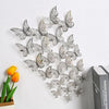 Silver 3D hollow butterfly wall decals set displayed on a white wall next to a book.