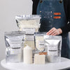 Set zum Herstellen von Soy-Wachs-Kerzen mit Wachs, Wickeln und dunkelblauem Apron auf weißem Untergrund.