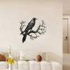 Black raven perched on a bare tree branch metal wall art displayed above a white sofa.