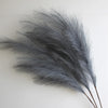 A bunch of gray artificial pampas grass branches used for boho home and wedding decor.