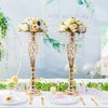 A set of gold crystal vases used as wedding centerpieces with floral arrangements on a white table.