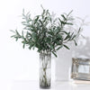 Artificial olive branch with green leaves and small fruits displayed in a clear glass vase.