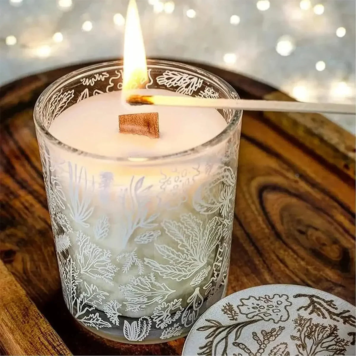 Un pot de bougie en verre transparent rempli de cire blanche et d'un pavot en bois, posé sur une surface en bois.