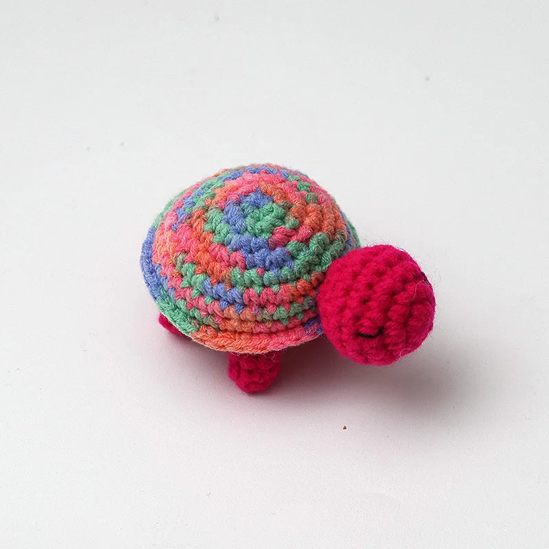 Handmade crocheted turtle plush toy with multicolored body and pink feet
