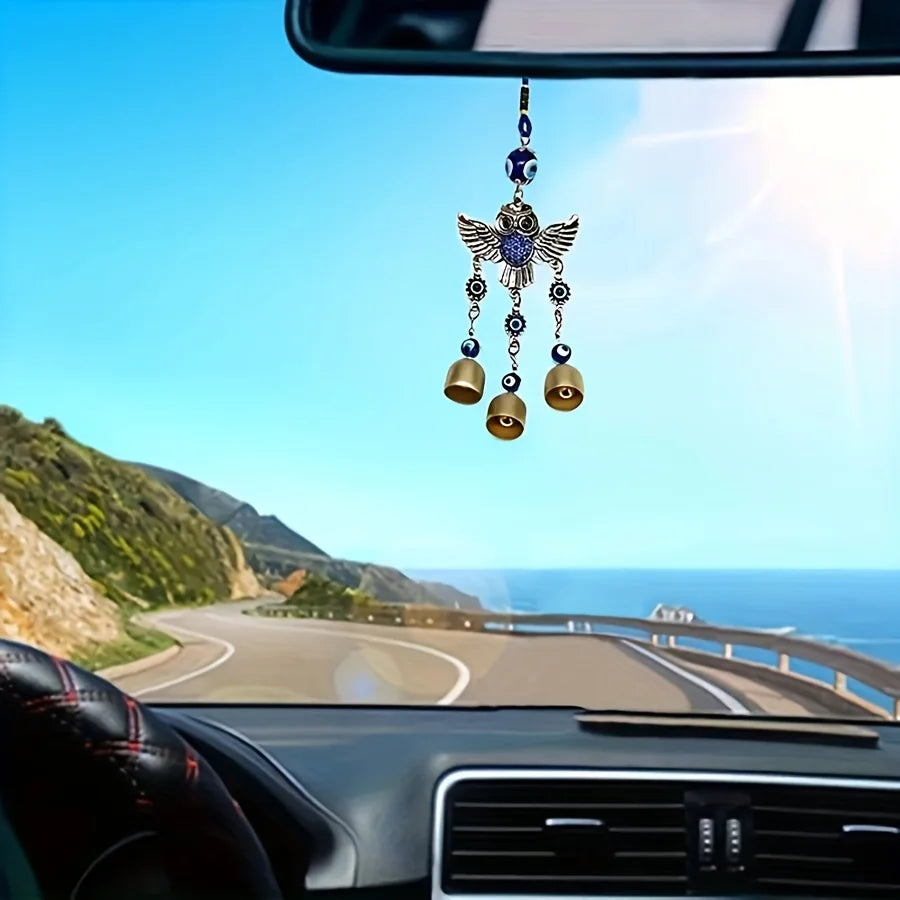 Cloche à vent avec une aile bleue, suspendue au rétroviseur d'une voiture.