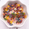 A bowl filled with colorful 3D resin flower gems in shades of yellow, pink, purple, and brown for crafts.