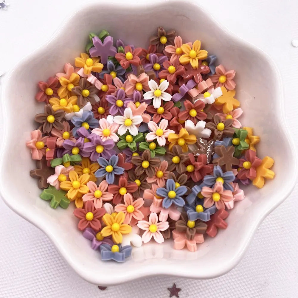 A bowl filled with colorful 3D resin flower gems in shades of yellow, pink, purple, and brown for crafts.
