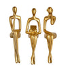 A set of three abstract thinker sculptures made of gold-toned resin.