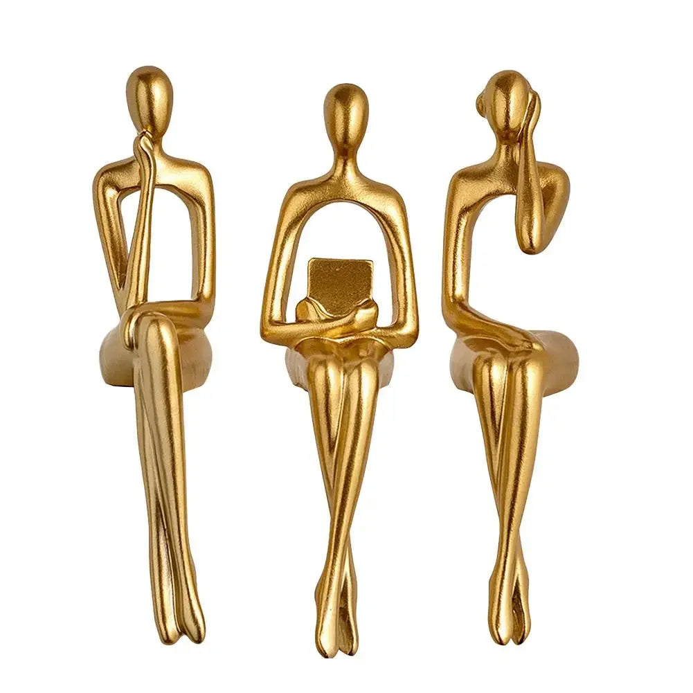 A set of three abstract thinker sculptures made of gold-toned resin.