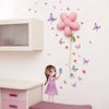 A young girl stands in front of a white wall decorated with pink and purple butterfly stickers and a large pink flower decal.