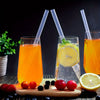 A glass of orange juice with a straw, garnished with lime, next to fresh red and black berries.
