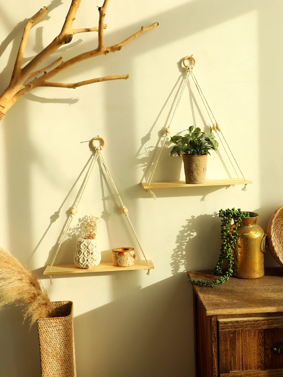A macrame wood floating wall shelf with hanging rope displaying plants and decorative items on a light-colored wall.