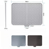 A silicone drain mat for a kitchen sink shown in light gray and dark gray colors.