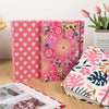 A set of pink and floral linen printed photo albums with decorative covers and a fresh pink rose.
